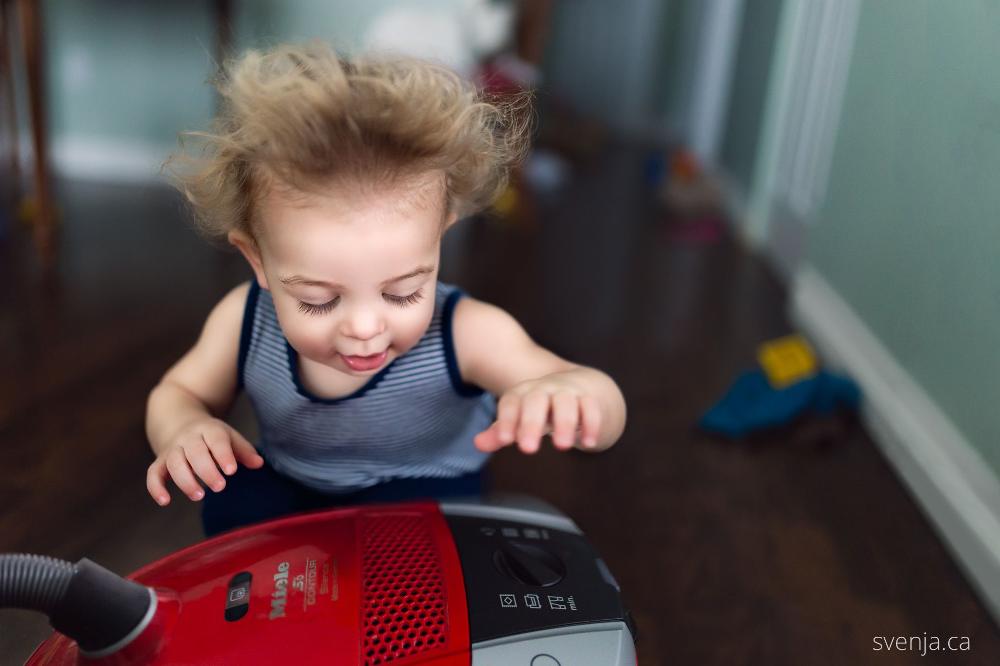 a boy's hair is wild as he experiences the exhaust of a vacuum cleaner