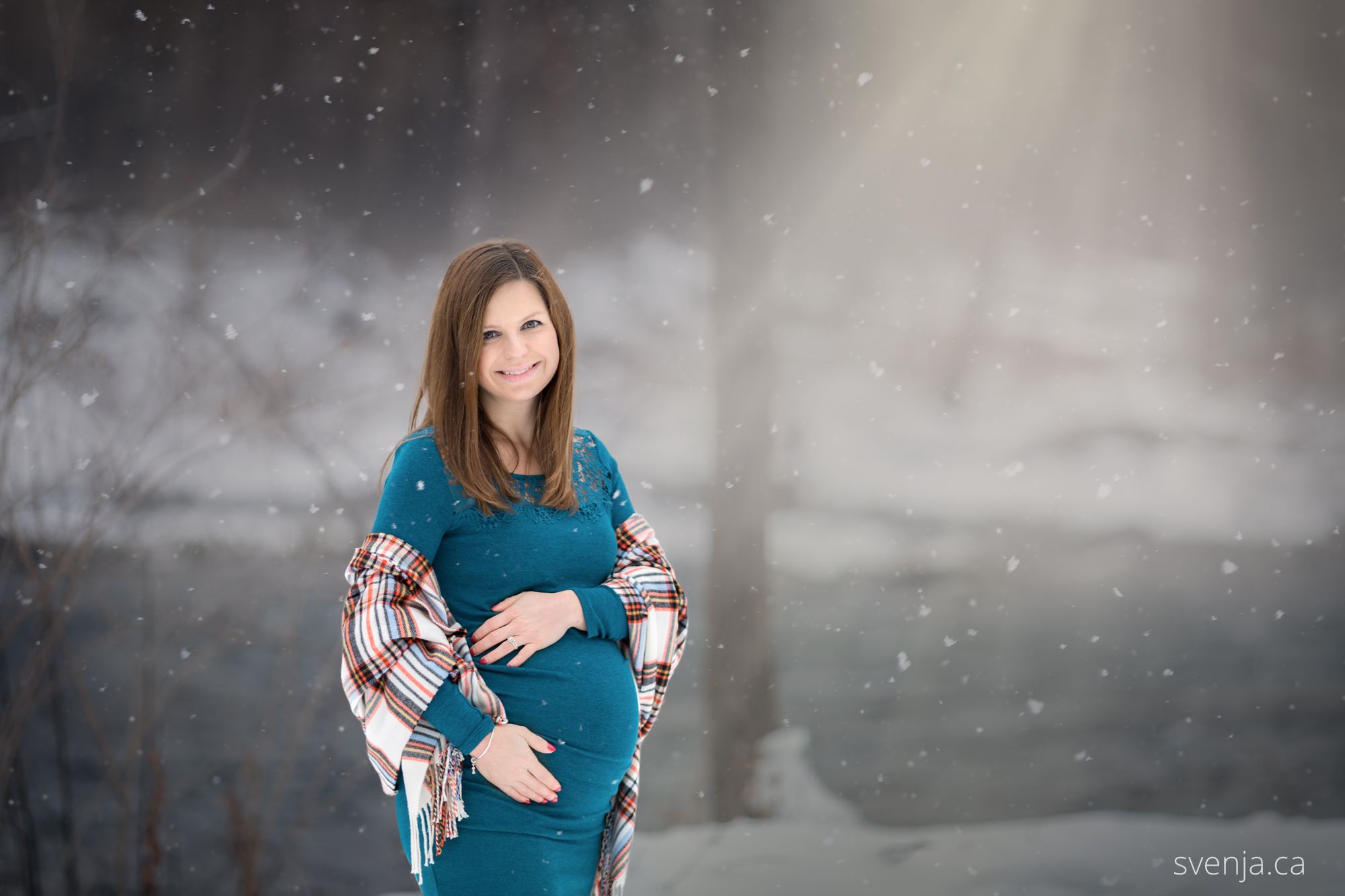 maternity picture with woman outside in the snow with sunlight