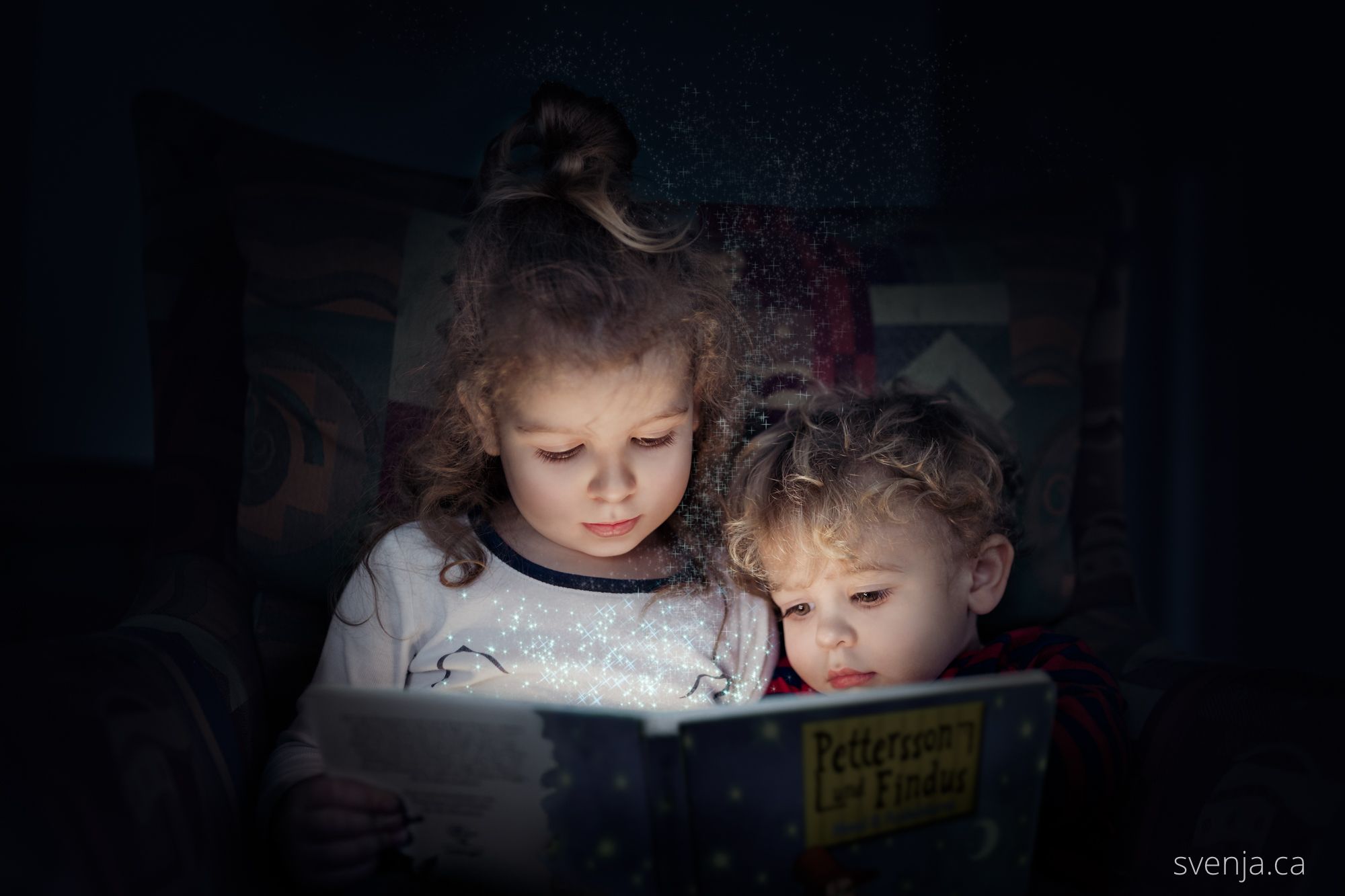 two young children sit on a chair and read a book together