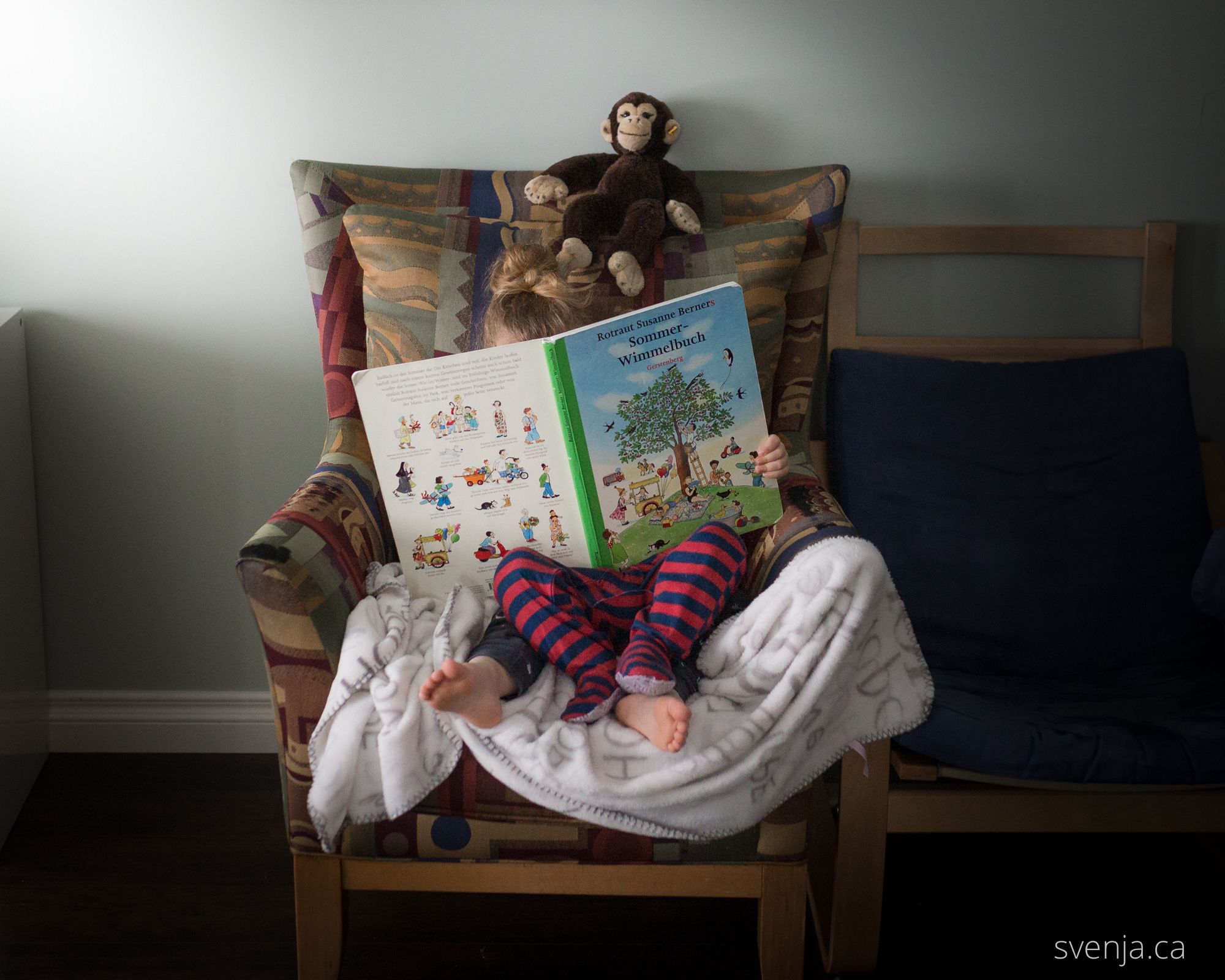 children sit on a green chair reading a book