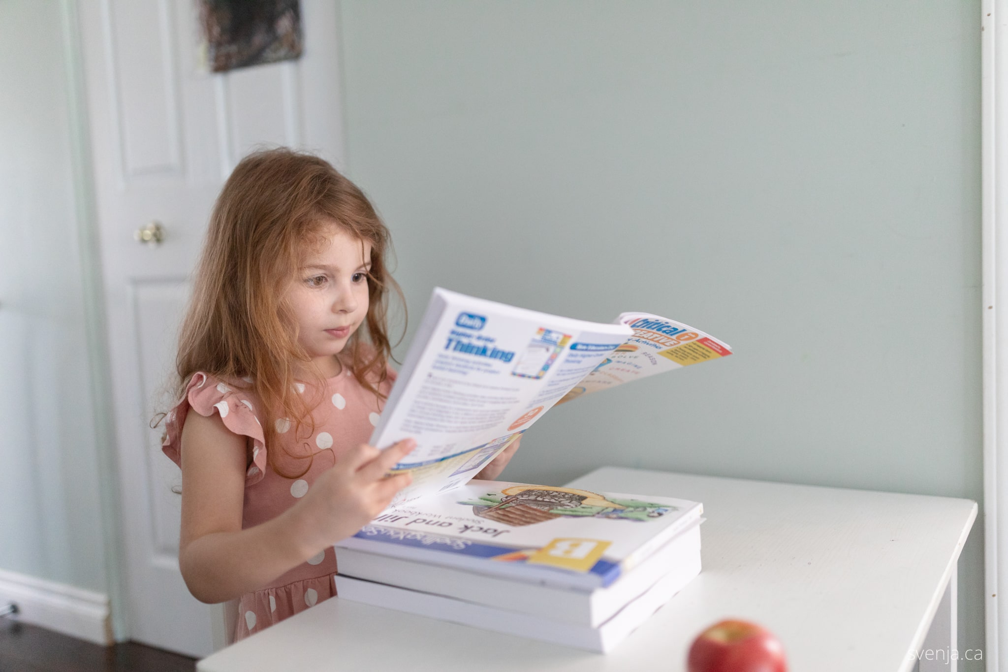 a young girl looks over a work book while seated at a desk