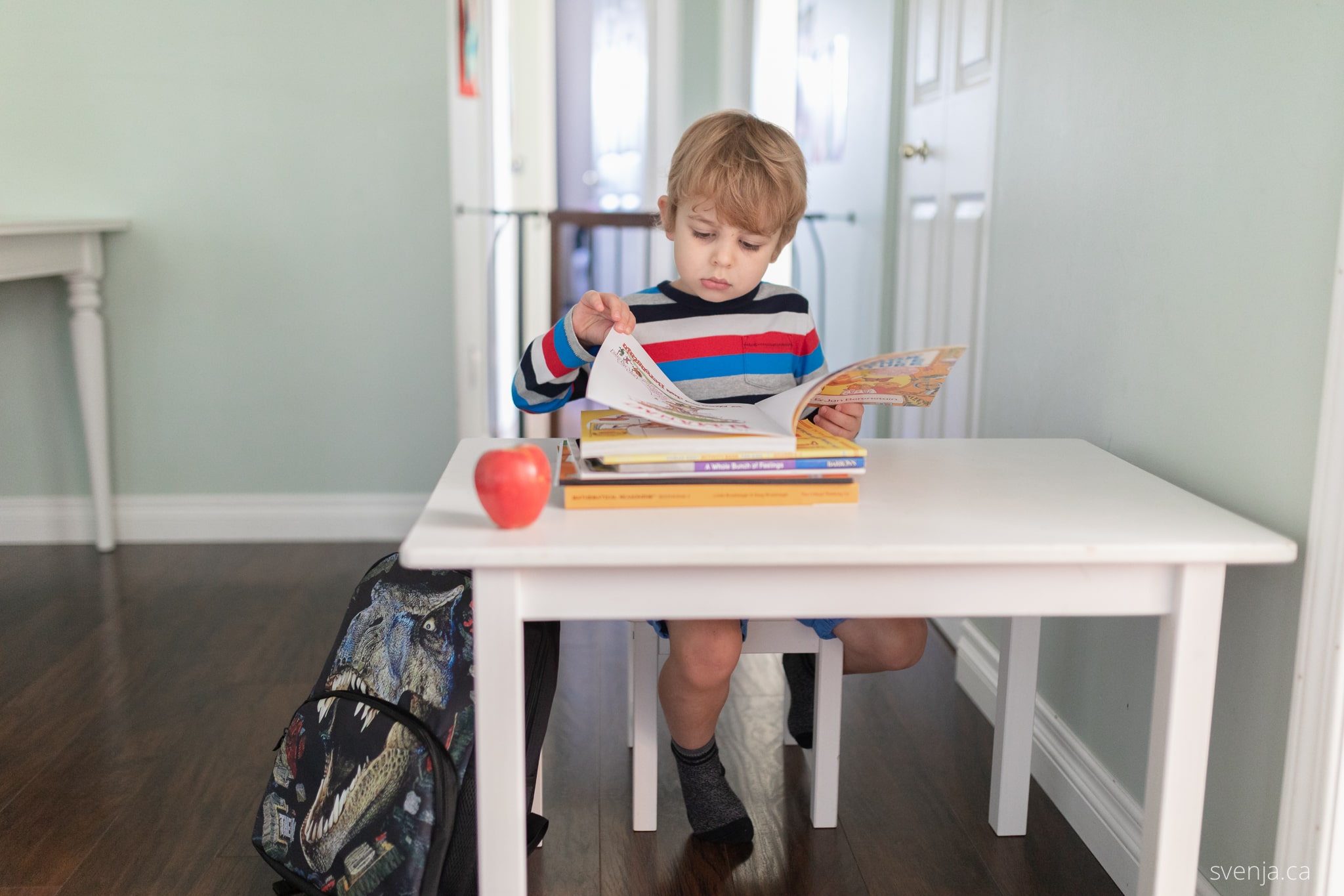 a young boy looks over a work book while seated at a desk