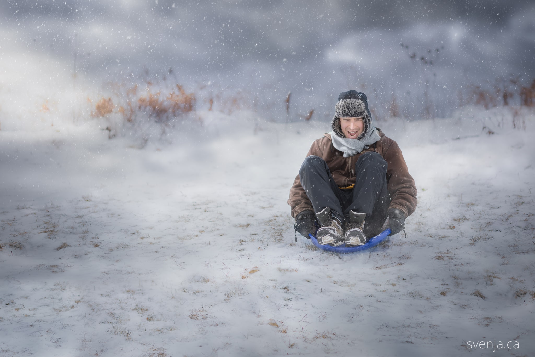 foolish man slides down a snowy hill in a child's toy