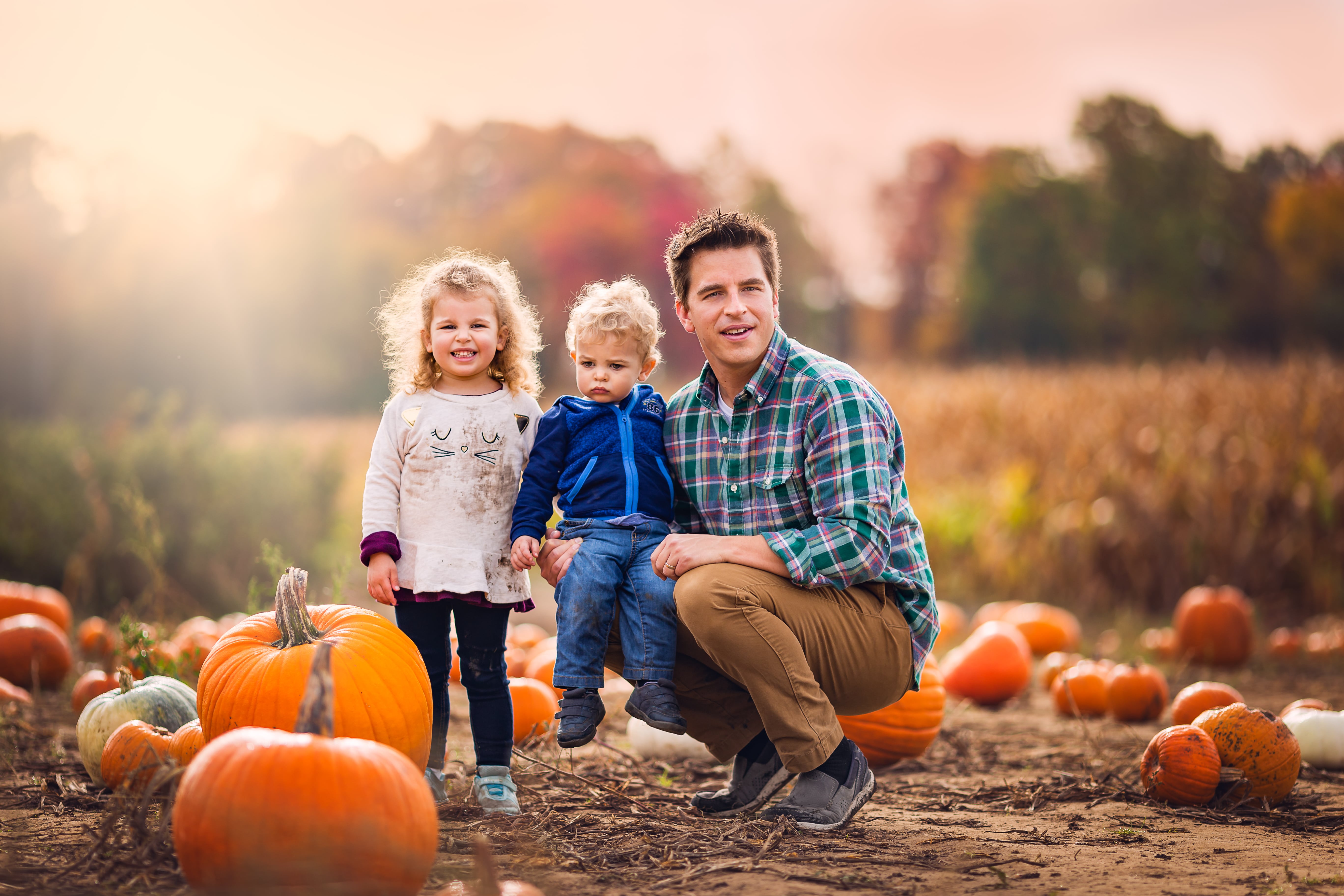 father and two children in a pumpkin patch