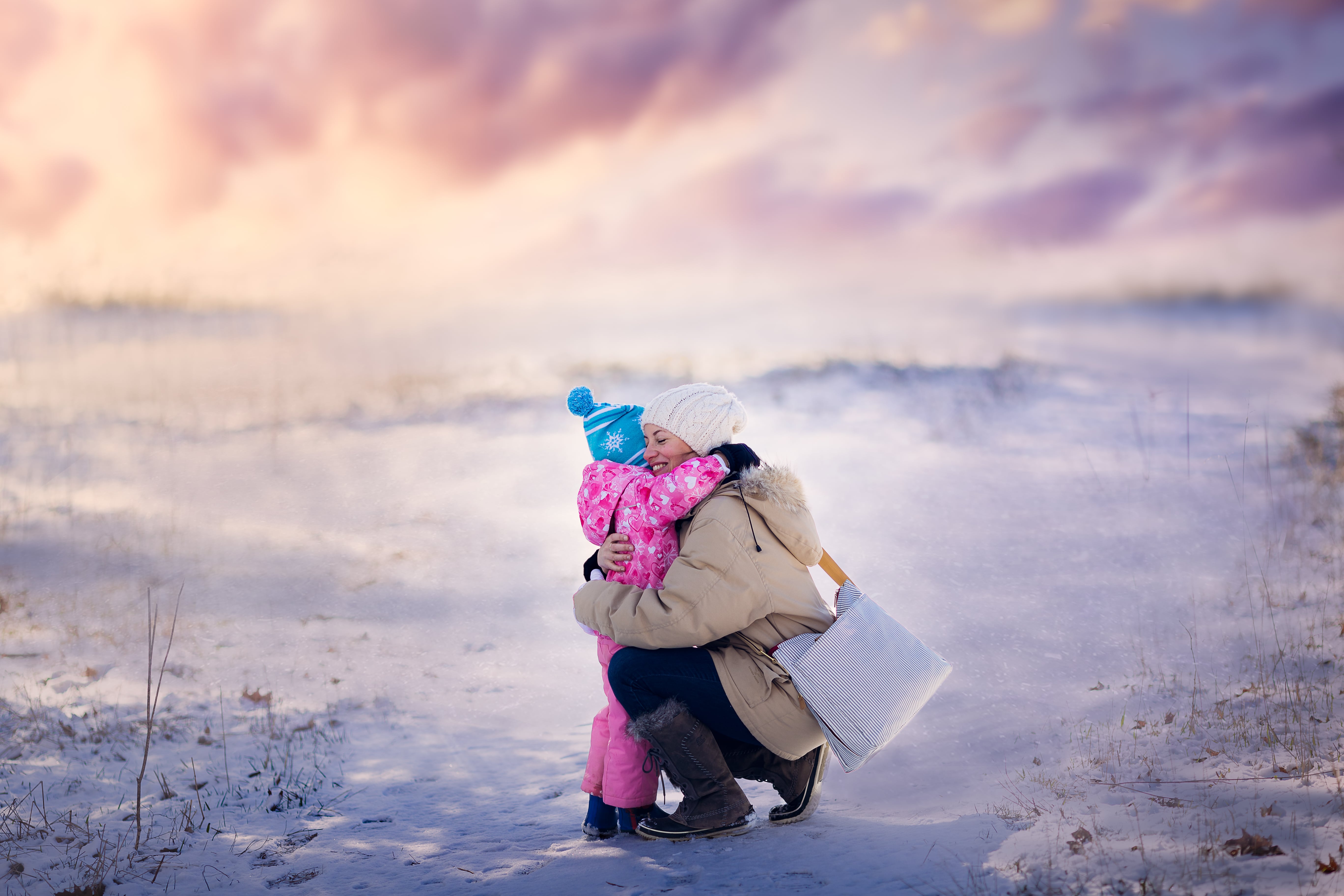 mother and daughter embrace in a snowy outdoor scene