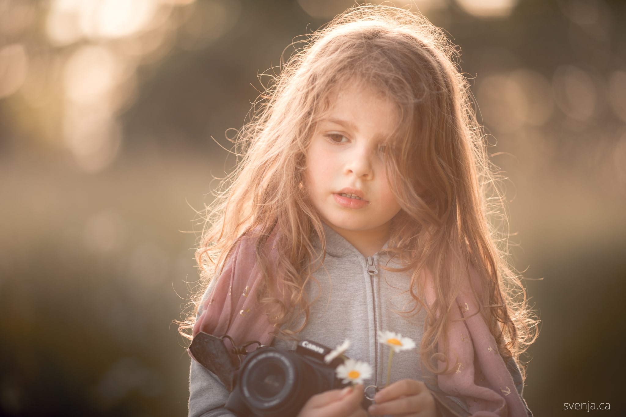 young girl holds a camera outside