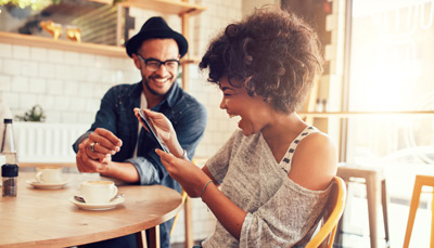 couple sitting at table laughing looking at a phone