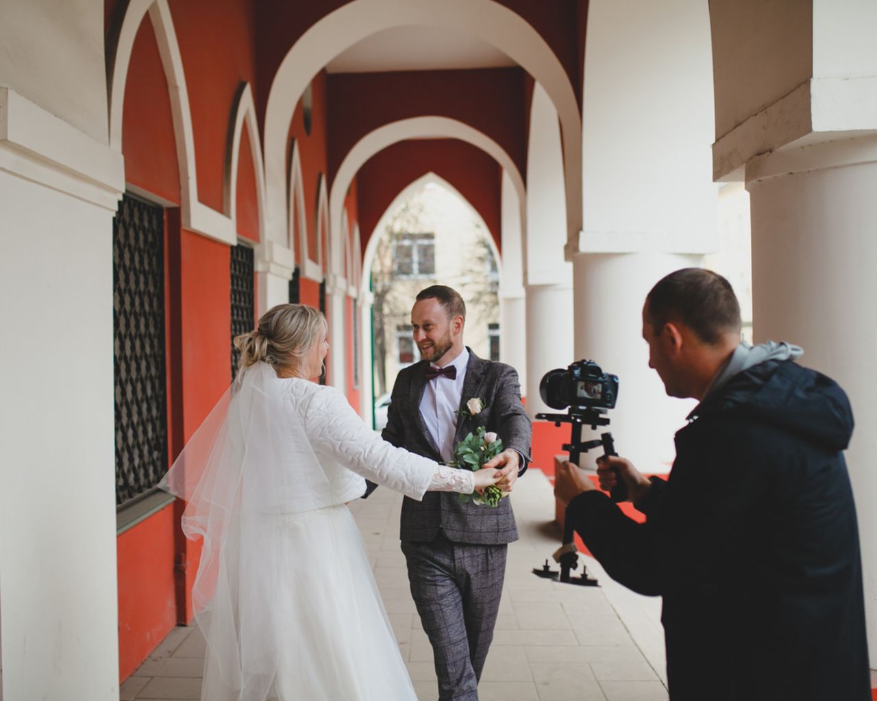 Wedding photographer taking pictures of the bride and groom in a gallery videograaf-filmt-bruidspaar-buiten-bij-gallerij