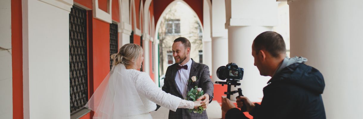 Wedding photographer taking pictures of the bride and groom in a gallery videograaf-filmt-bruidspaar-buiten-bij-gallerij