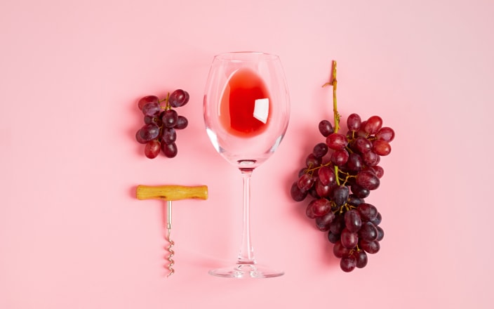 Empty glass of red wine laid flat with grapes and a corkscrew (preview)