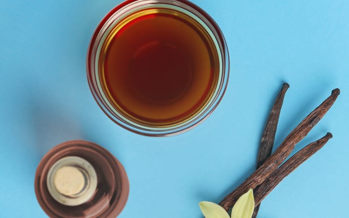 Glass of whiskey and vanilla bean against a blue background (preview)