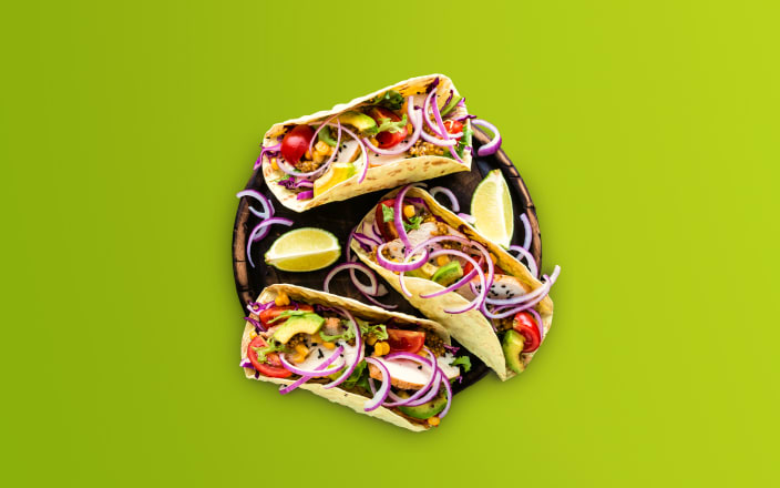 Three tacos with avocado, red onion, and tomatoes on top for Confetti's Virtual Taco Making Class