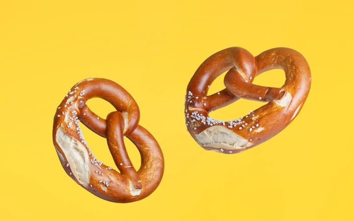 Traditional German salted pretzels floating against a yellow background (preview)