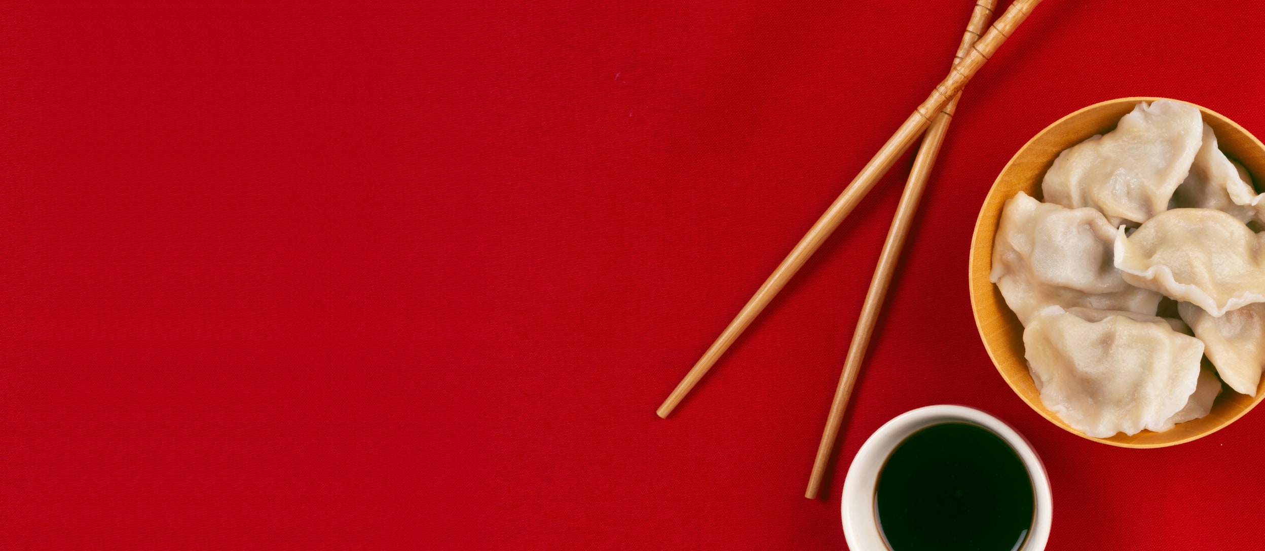 Dumplings in a bowl next to chopsticks and soy sauce for Confetti's Virtual Asian Cooking Classes