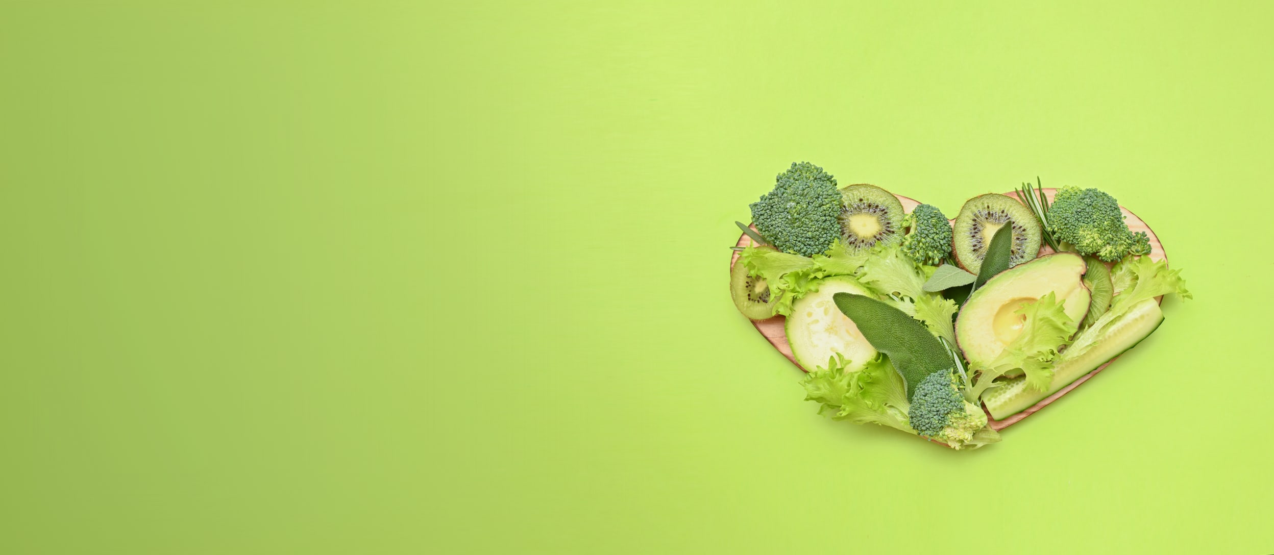 Green fruits and vegetables on a heart-shaped cutting board (large)