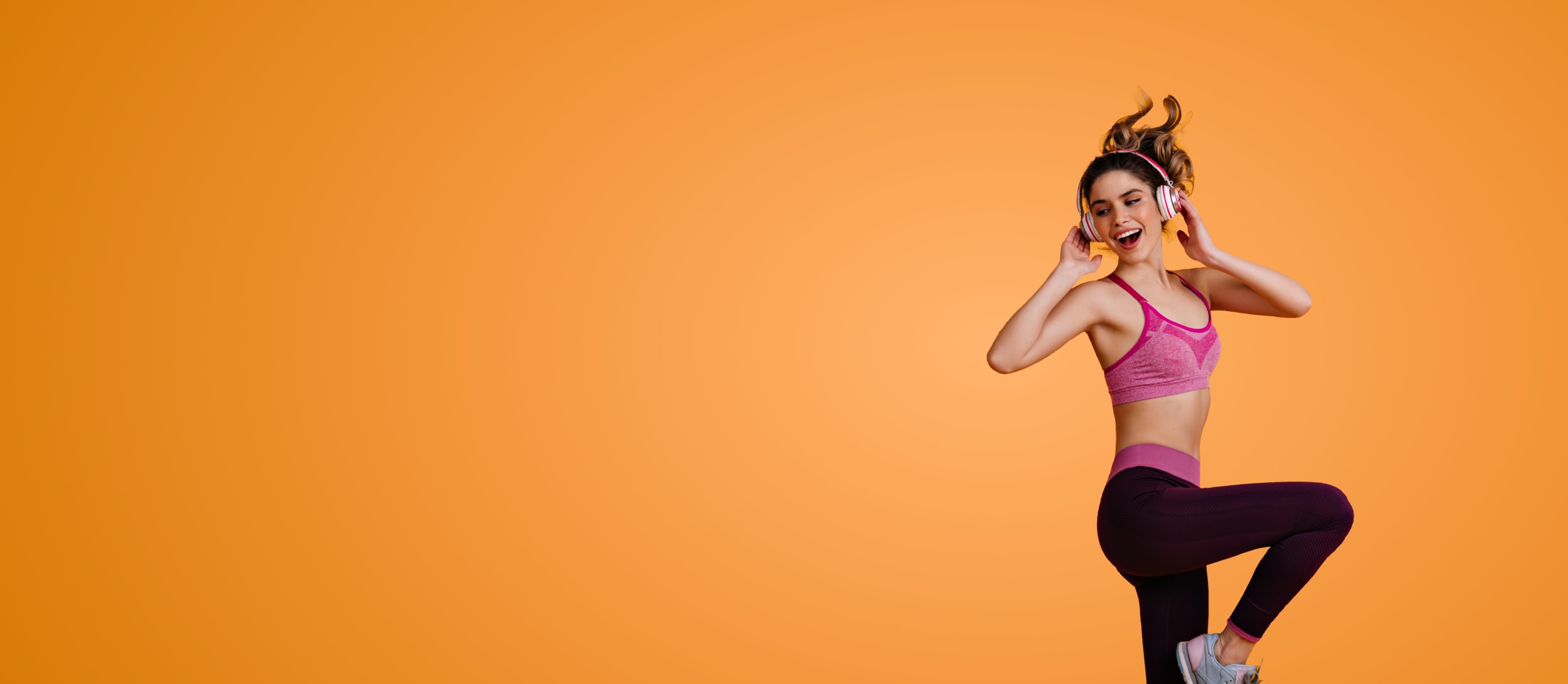 A happy girl dancing and listening to music on her headphones for Confetti's Virtual Dance Class