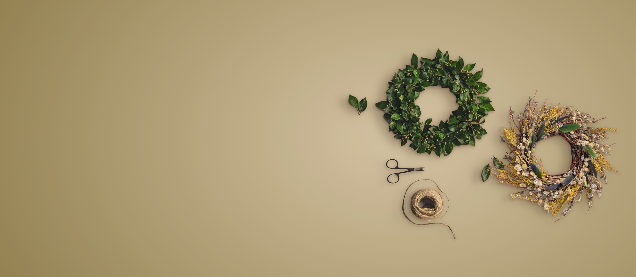 Scissors and twine next to a green wreath and a gold and tan decorative wreath for Confetti's Virtual Holiday Wreath Workshop