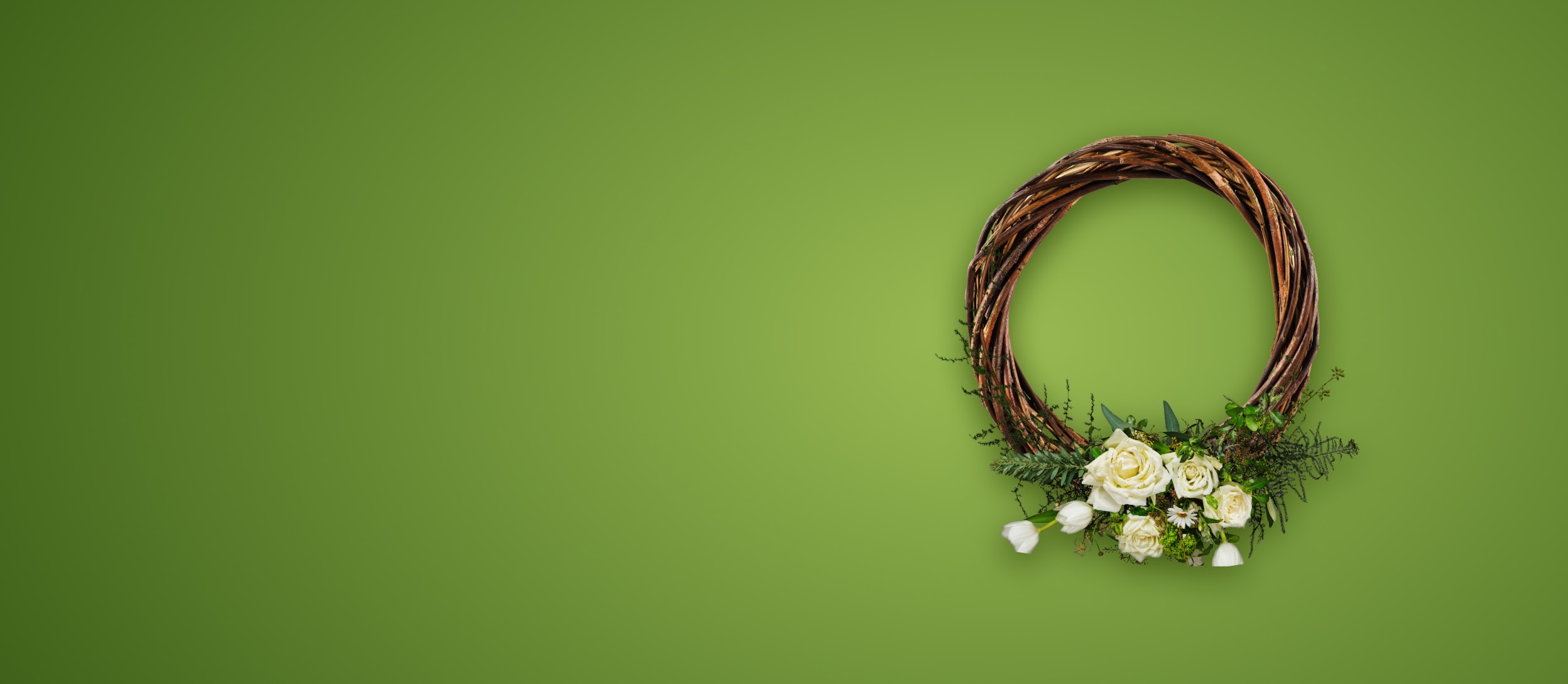 A brown wreath with white spring florals and greenery at the bottom for Confetti's Virtual Floral Wreath Making Class