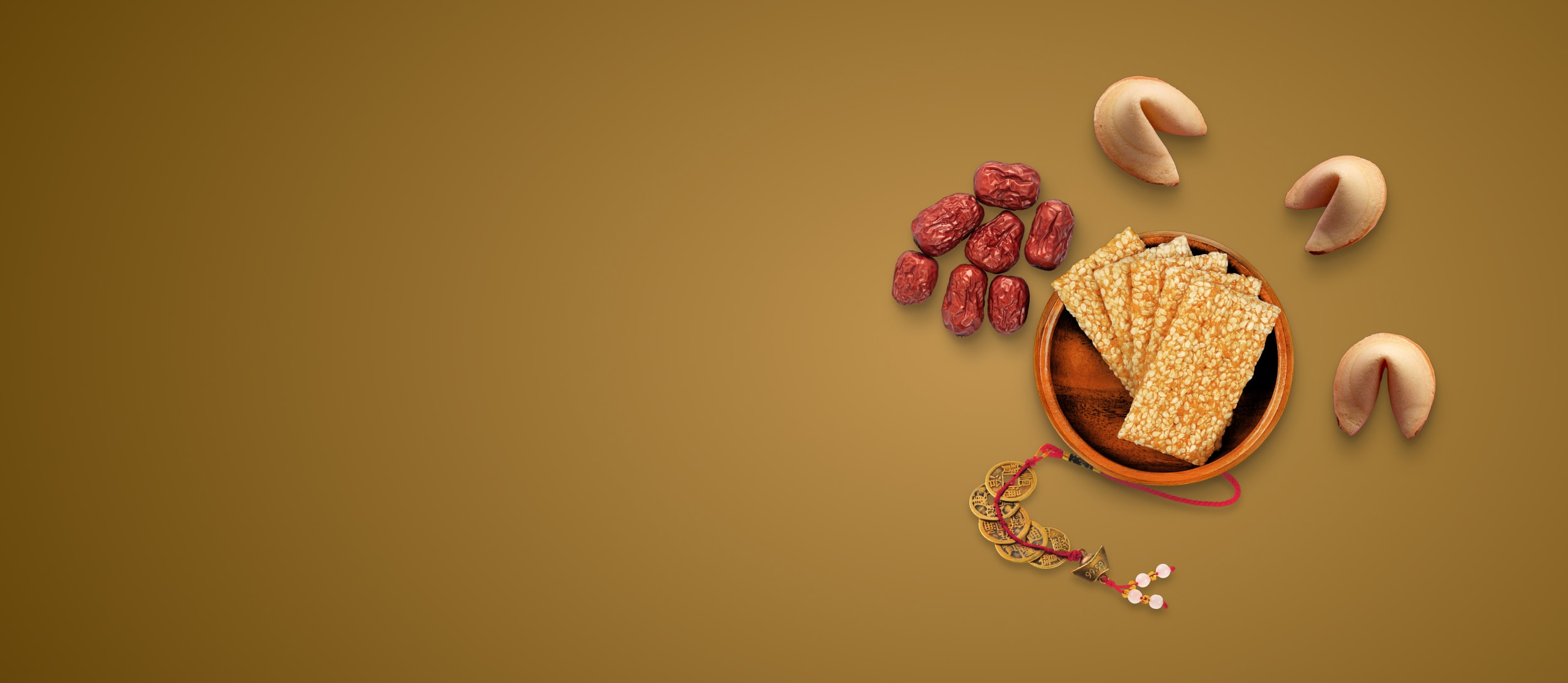 A bowl of sesame crackers next to gold coins, dates, and fortune cookies for Confetti's Asian Snack Box