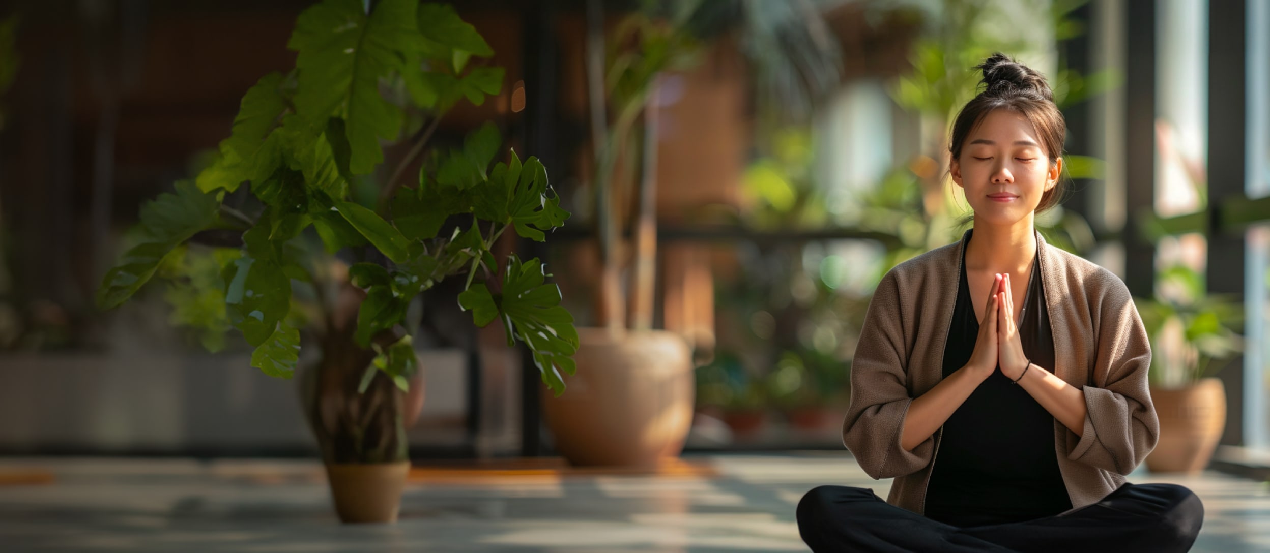 Woman meditating in a yoga pose in a bright room with plants (large)