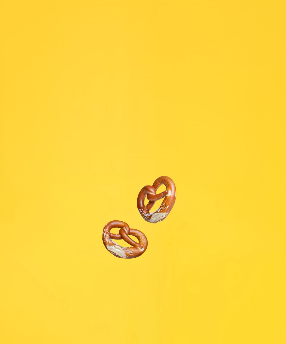 Traditional German salted pretzels floating against a yellow background (small)