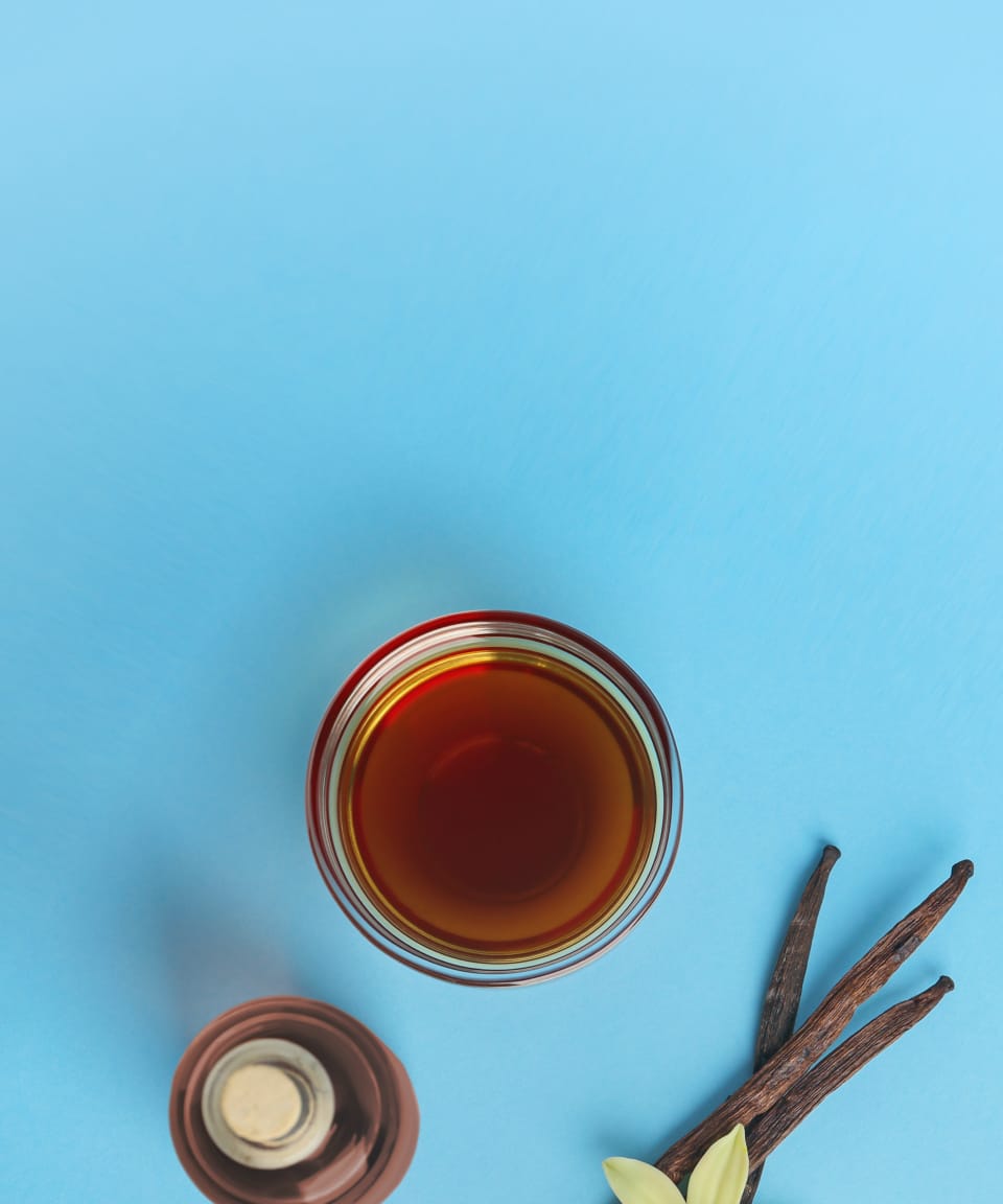 Glass of whiskey and vanilla bean against a blue background (small)