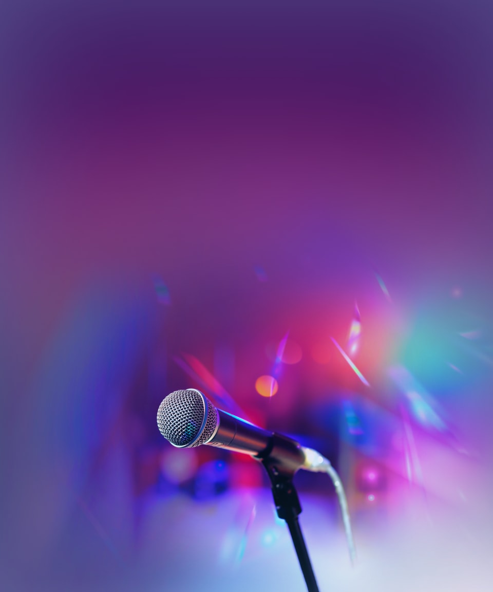 A microphone in front of colorful concert lights for Confetti's Virtual Pride Pub