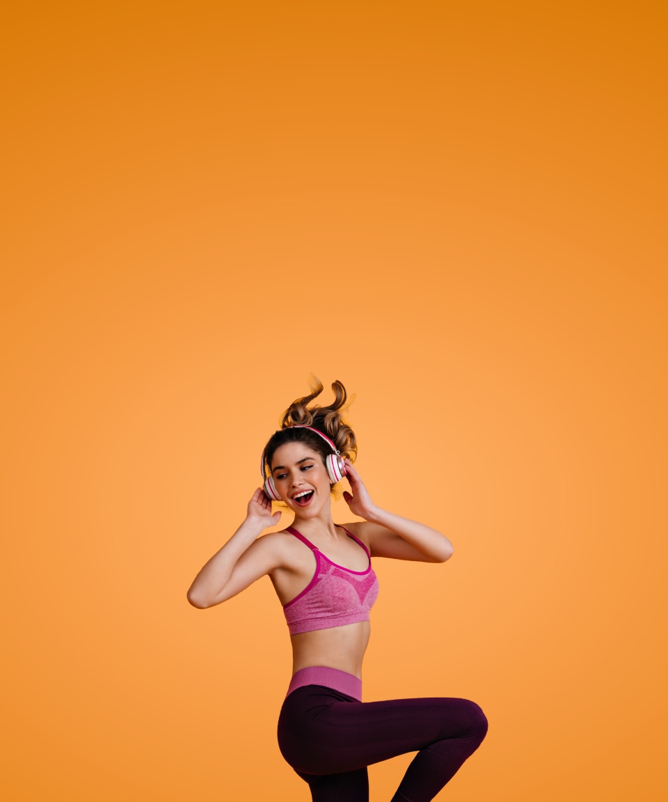 A happy girl dancing and listening to music on her headphones for Confetti's Virtual Zumba Class