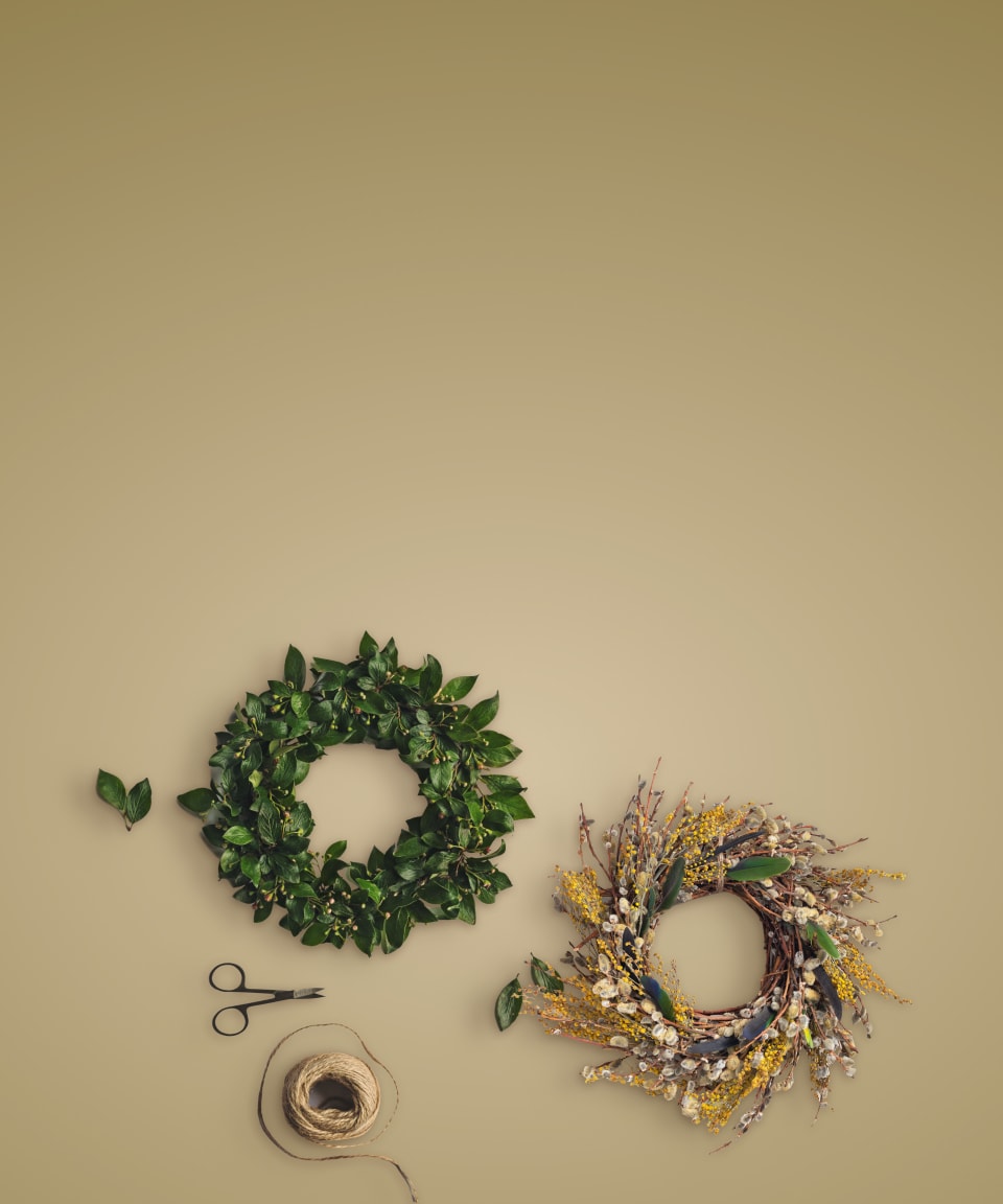 Scissors and twine next to a green wreath and a gold and tan decorative wreath for Confetti's Virtual Holiday Wreath Making Class