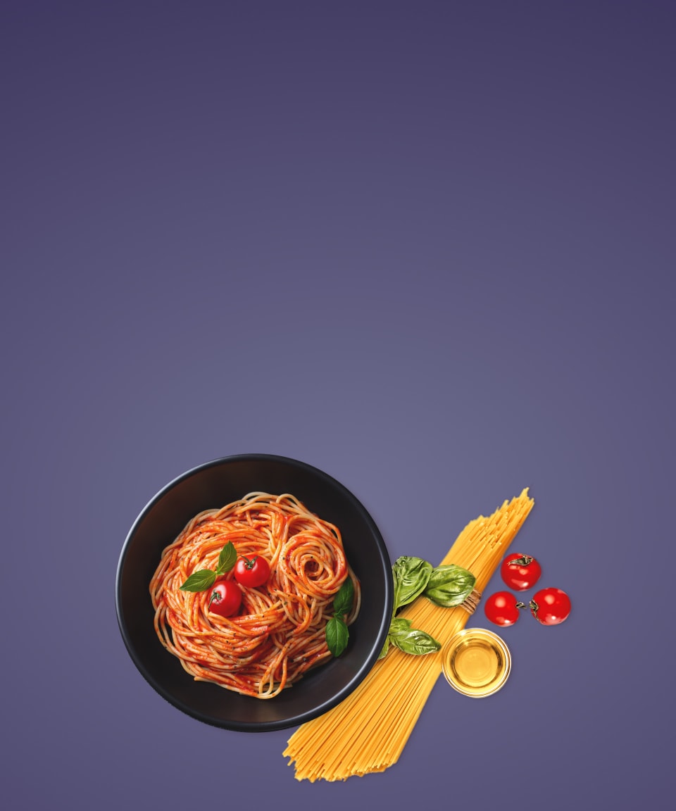 A plate of spaghetti next to a bundle of pasta, basil, and tomatoes for Confetti's Virtual Pasta Making Class