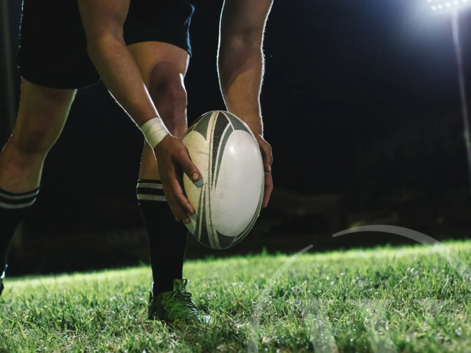 A man's arms and hands holding a rugby ball