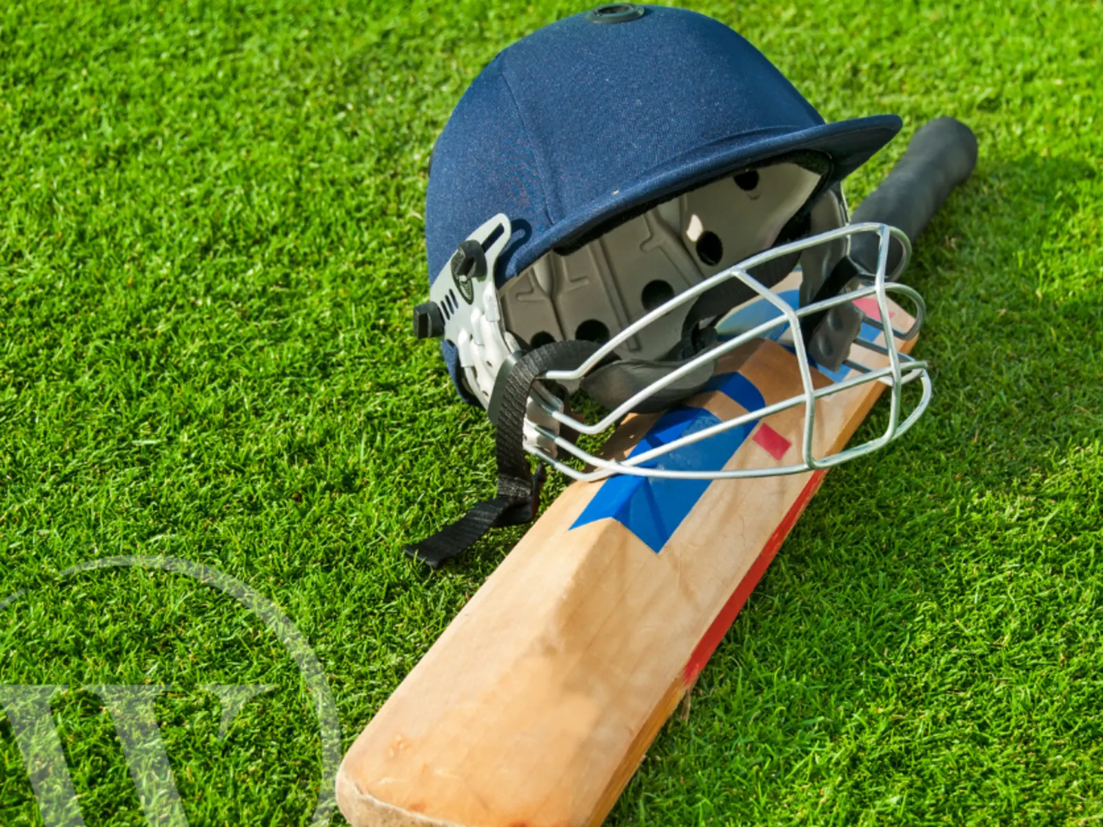 A cricket bat and helmet on a cricket field