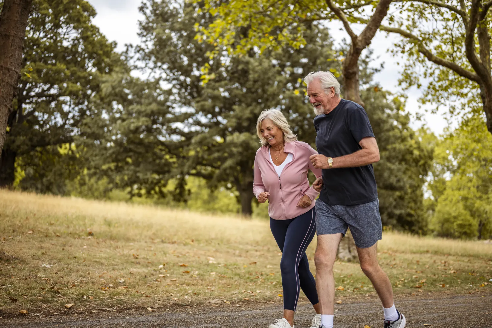 2 elderly people running in the park