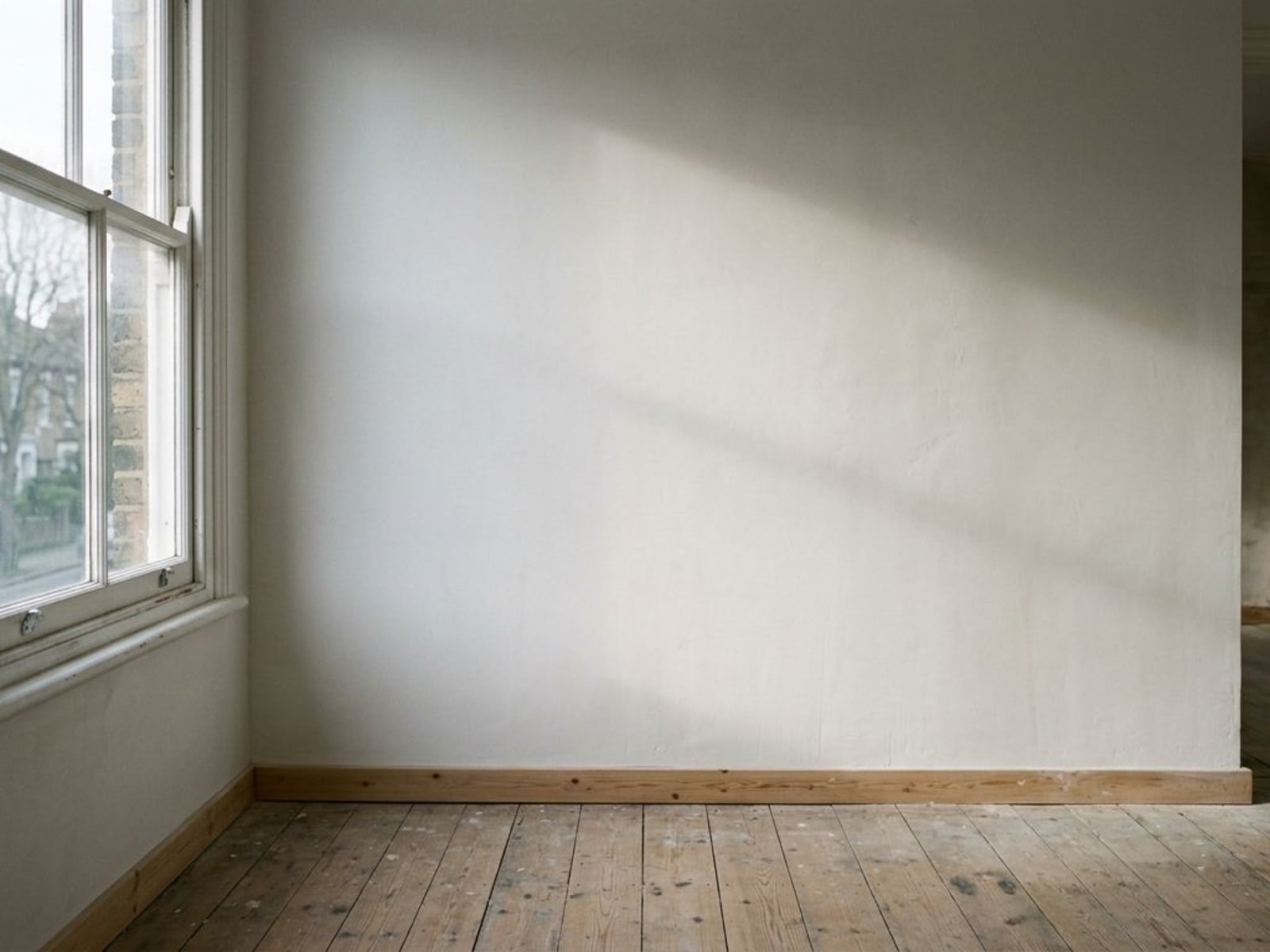 Raking daylight across a finished skimmed wall showing surface flatness