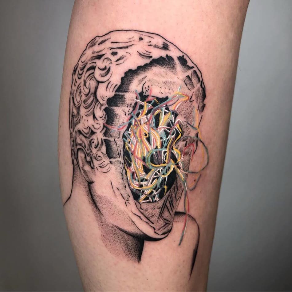 Tattoo showing a statue with embroidery wires by Jordy Rios