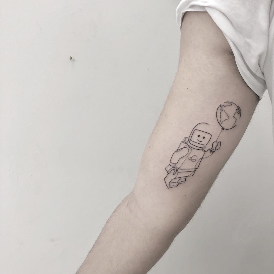 Lego figure with earth as a balloon tattoo