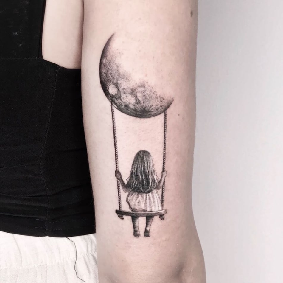 Girls sitting on a swing that hangs from the moon tattoo by Maya Gat