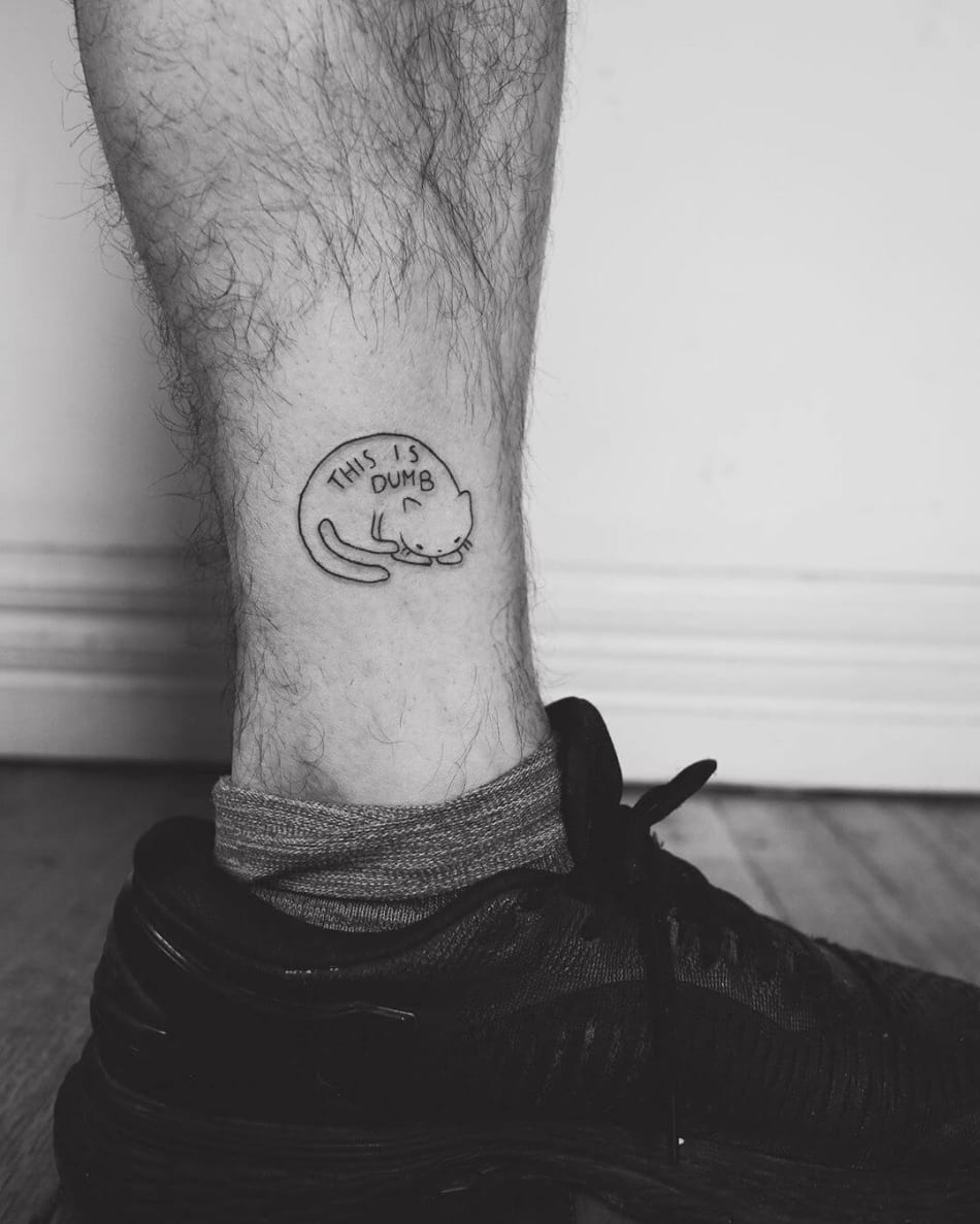 Cat with the text 'This is dumb' tattoo by Phoebe Hunter