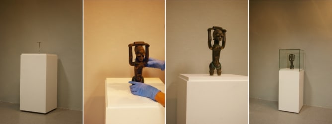 Wooden pedestals with a small statue placed in a display case