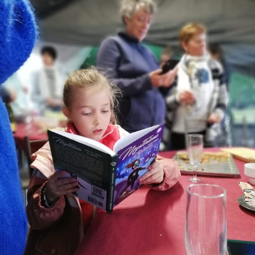 Un livre Mystériane qui finit sur une table, au milieu d'une fête de famille