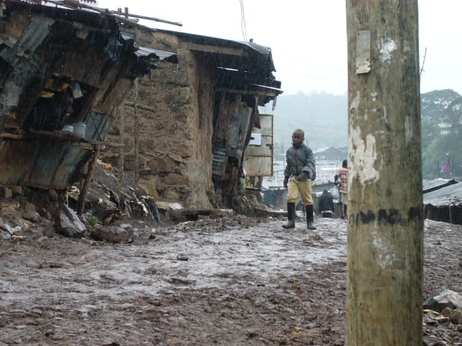 Kind im Regen im Slum unterwegs.