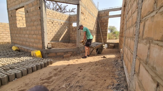 Joel beim Befúllen des Zimmerbodens mit Sand.