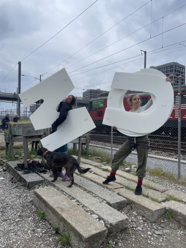 Unsere wunderbaren Akrobatinnen belmontearts und anjalunacirque wärmen sich bereits auf für die performative Anbringung der letzten Buchstaben.