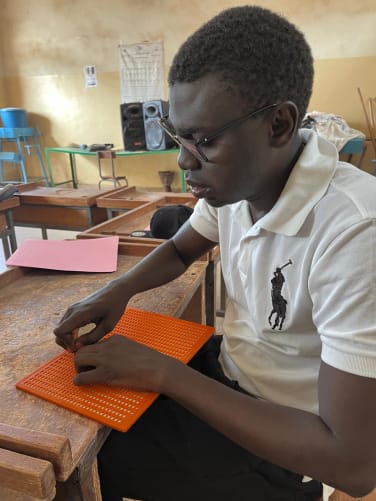 Dominique en classe, en train d'écrire un texte en braille.