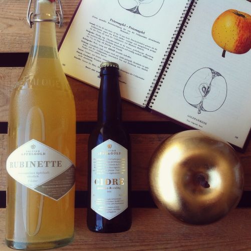 Abbildung einer Goldparmäne, eine Flasche Most Jahrgang 2015 und eine Flasche Cidre