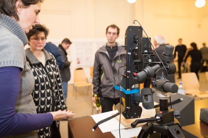 A device for material analysis is demonstrated to research colleagues.