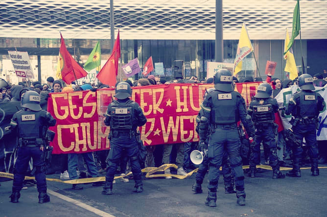 Demonstrierende vor eine Polizeikette am Messeplatz.