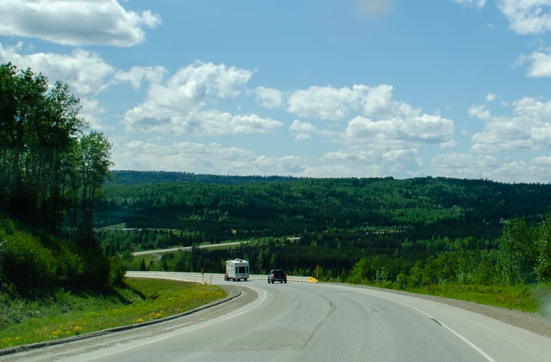 the alaska highway going through rolling hills and green forests