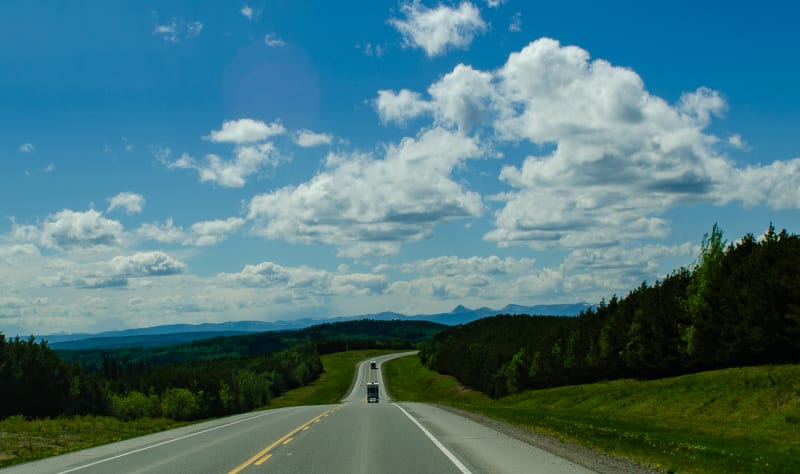 the alaska highway going through rolling hills and green forests