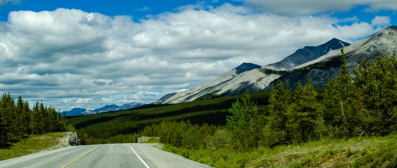 road drops into a valley with high peaks along the side